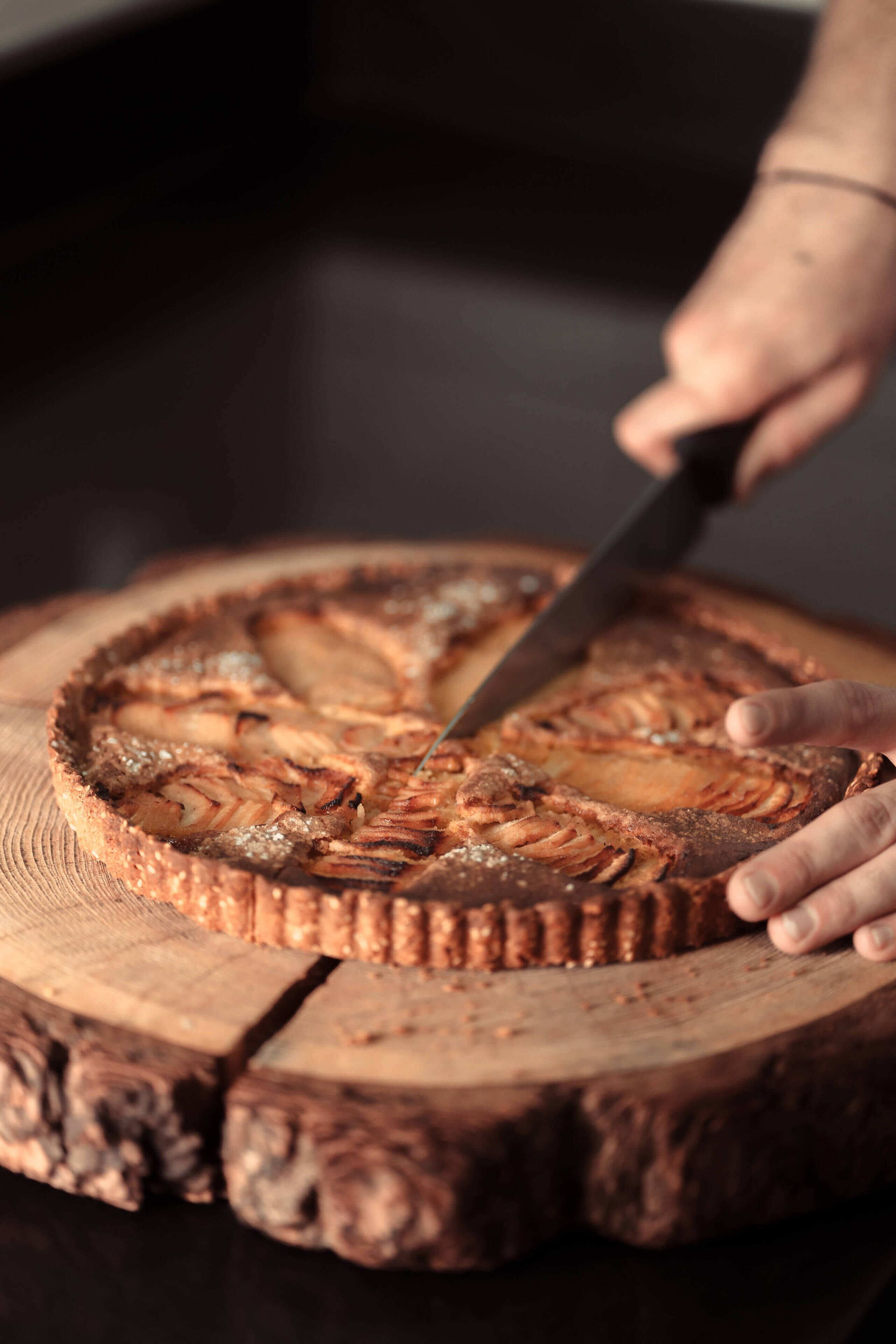 Une personne qui découpe un gâteau sur une planche en bois.