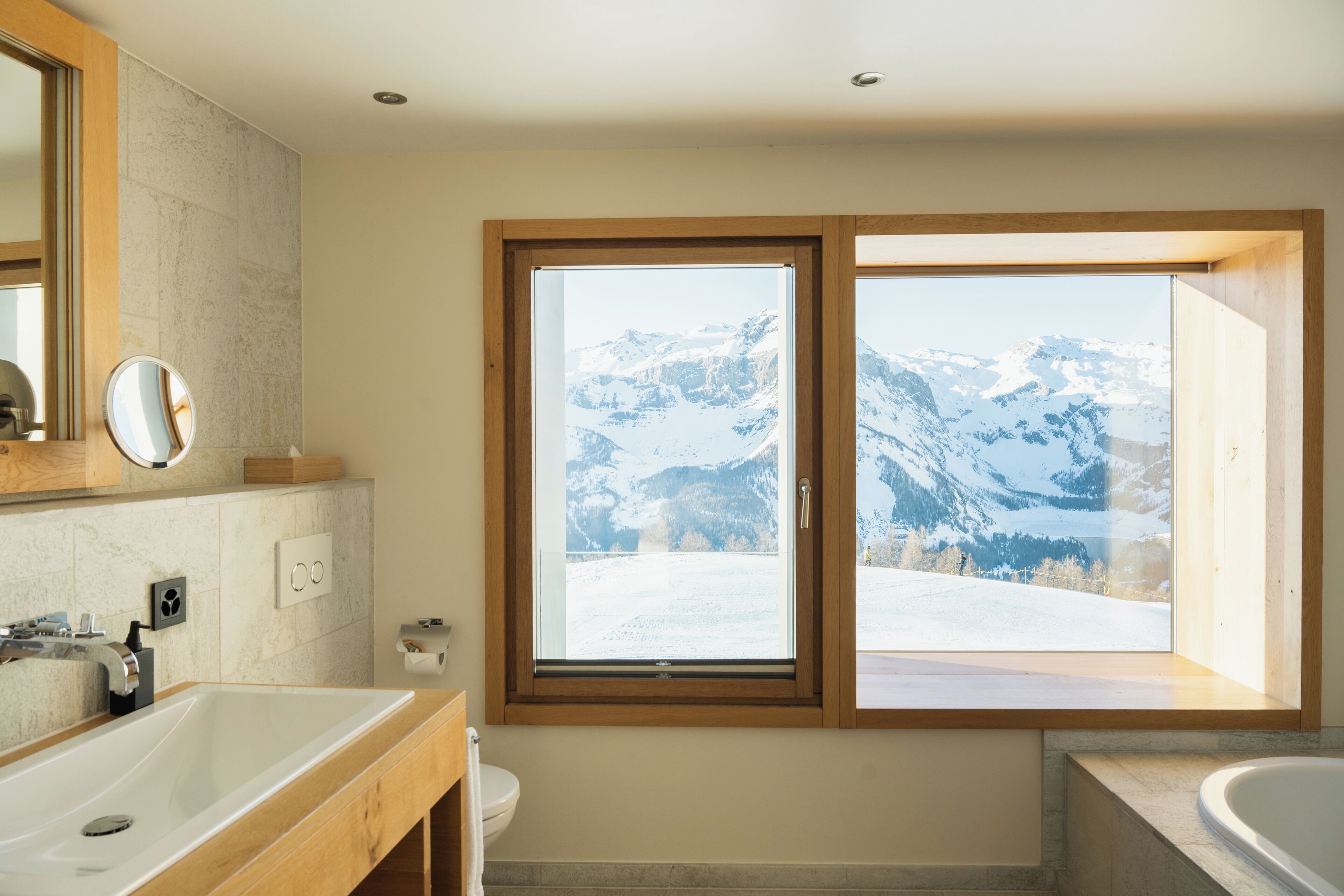 A bathroom with a large window, a sink, and a bathtub.