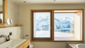 A bathroom with a large window, a sink, and a bathtub.