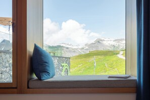A window seat with a cushion, overlooking a mountainous landscape with a clear sky.