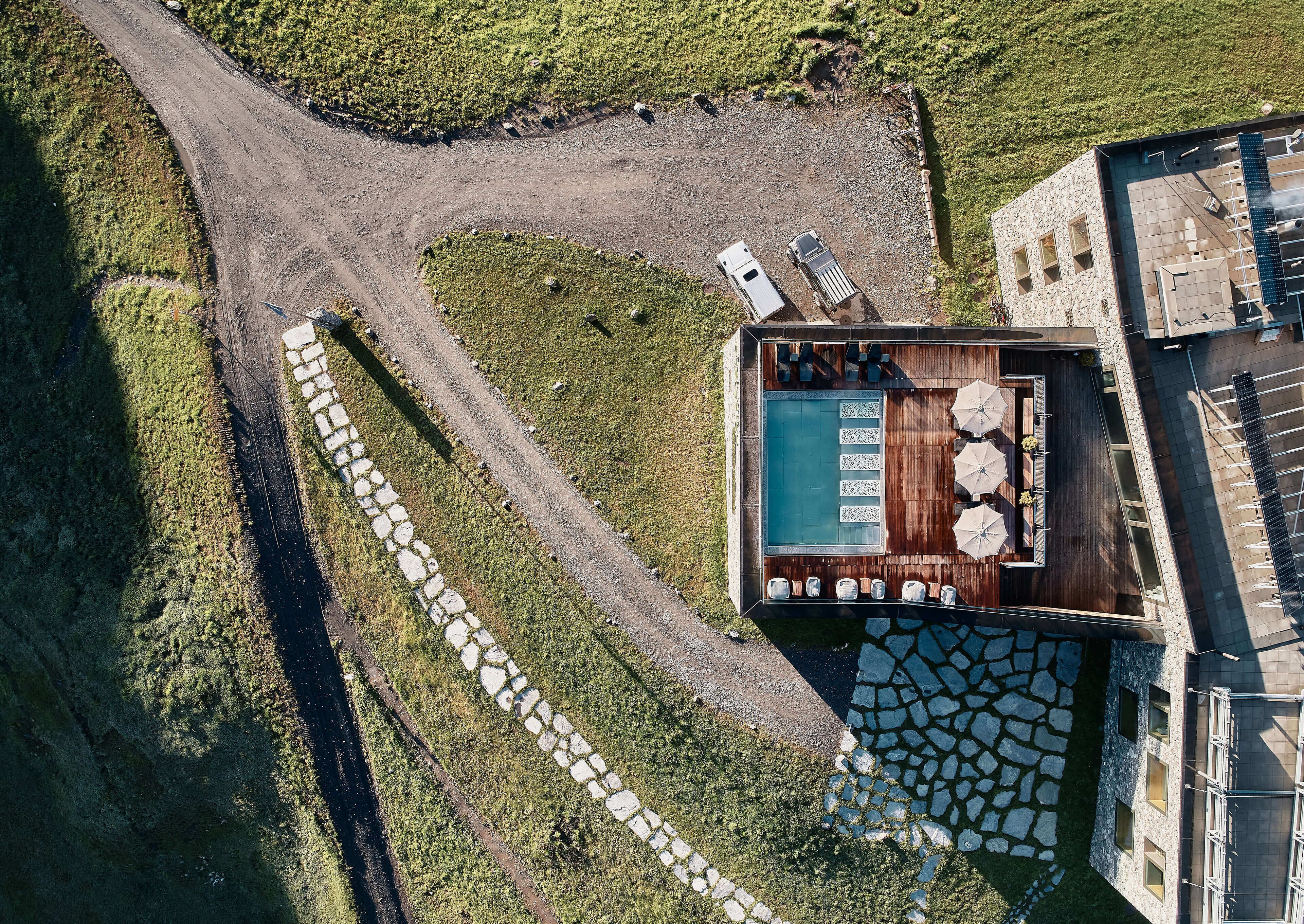 An aerial view of a resort with a swimming pool, outdoor seating, and a stone pathway.