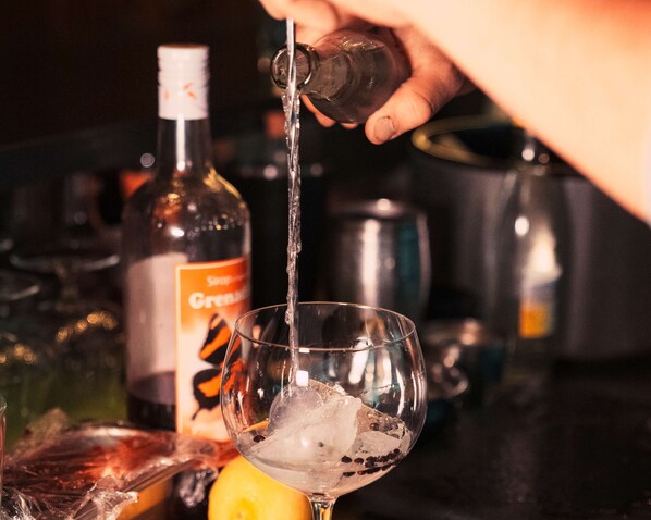 A hand pouring a clear liquid into a glass with ice cubes. - Chetzeron (Crans)