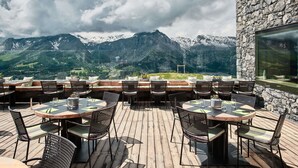 An outdoor dining area with tables and chairs, overlooking a mountainous landscape. - Chetzeron (Crans)
