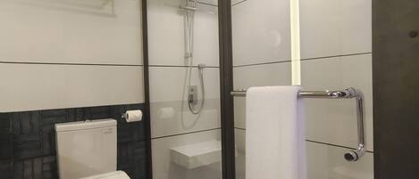 A modern bathroom with a toilet, a glass-enclosed shower, and a towel rack.