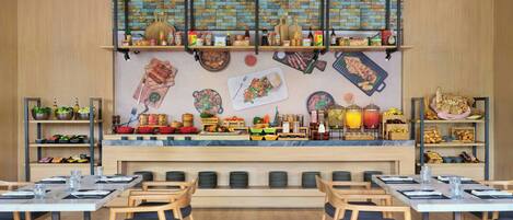 Un restaurante con una barra larga, diversas opciones de asientos y una variedad de alimentos exhibidos en estantes y la barra.