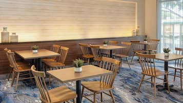 A restaurant with wooden tables and chairs, a patterned floor, and a large window with natural light.