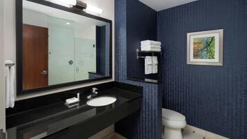 A modern bathroom with a black sink, a large mirror, a toilet, and a towel rack.
