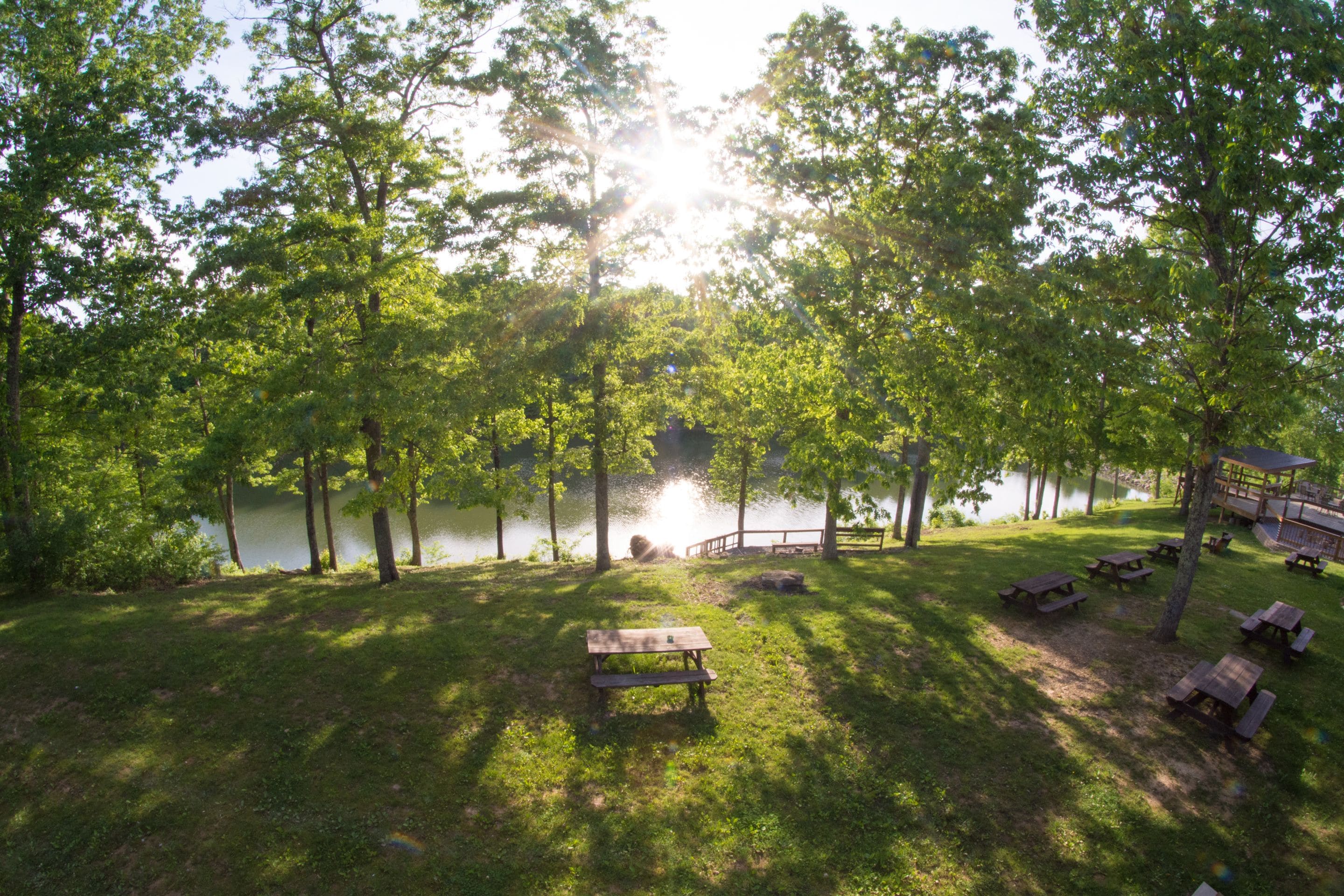 Un parque junto al lago con mesas de picnic y un pabellón.
