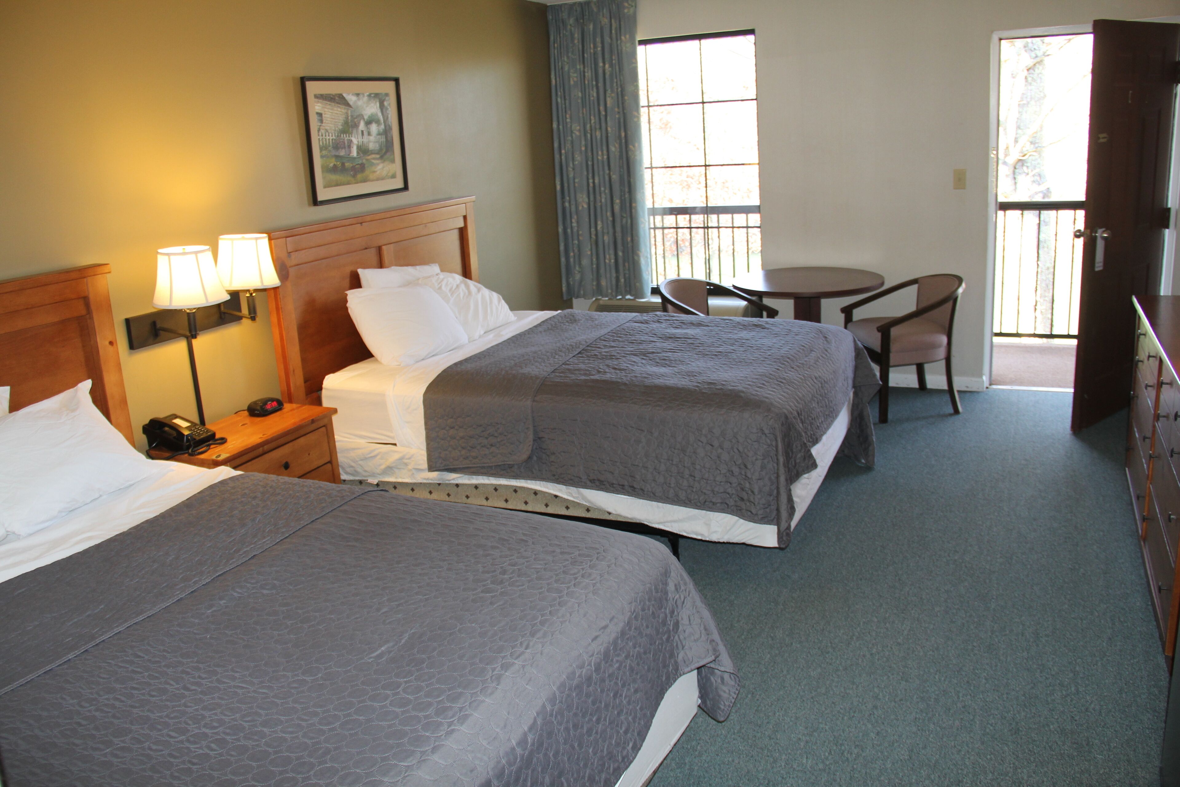 A hotel room with two beds, a desk, a chair, and a window with curtains.