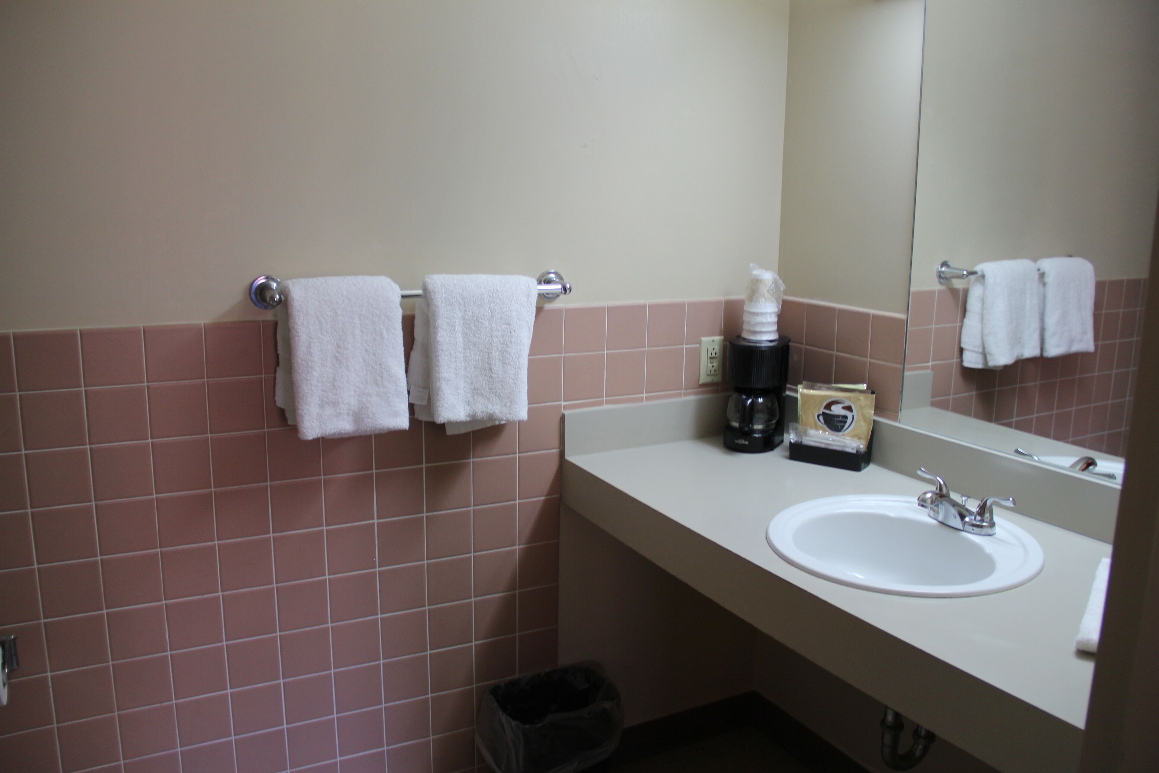 A bathroom with a sink, mirror, and two towels hanging on a rack.