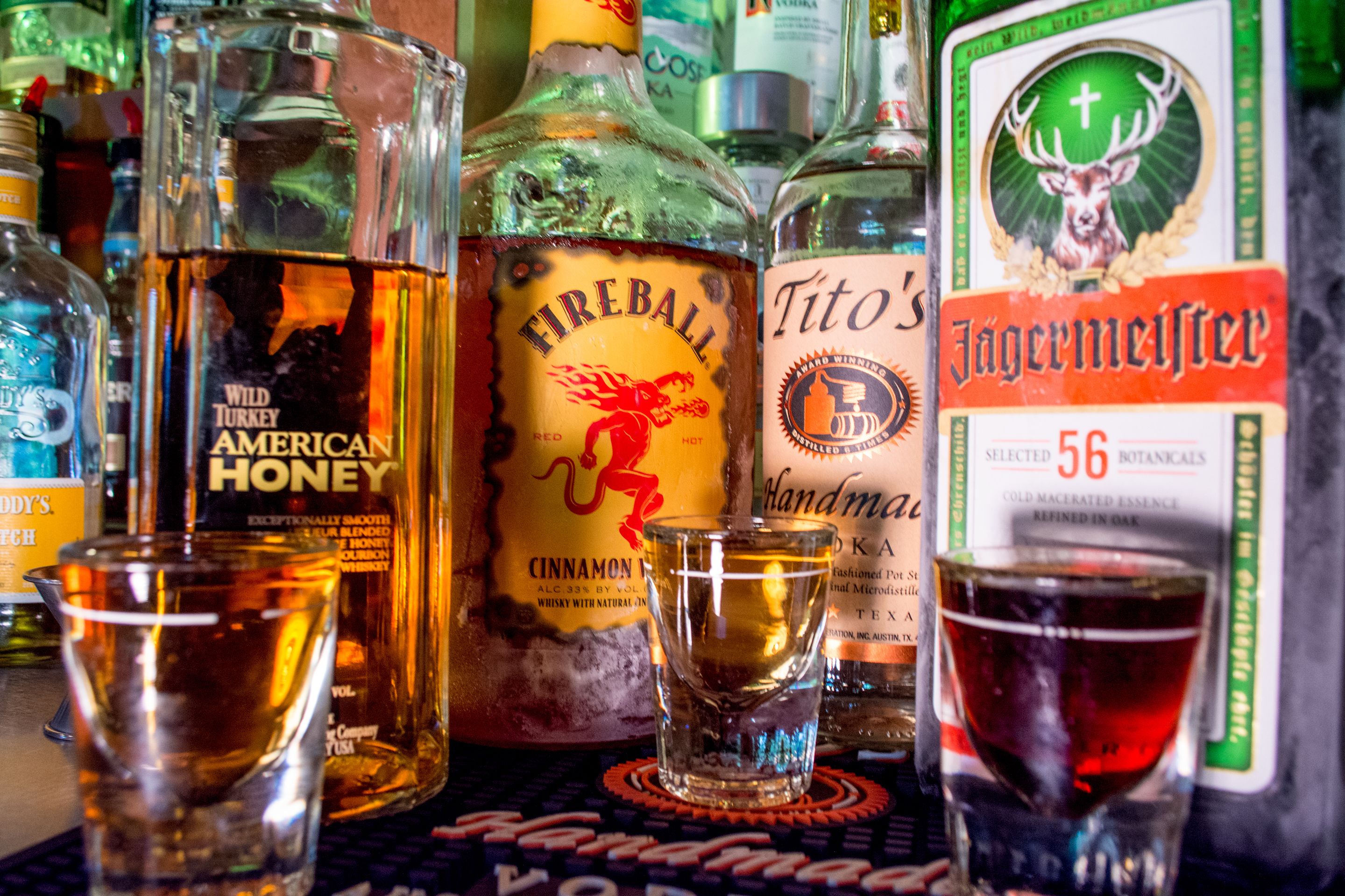 Verschillende drankflessen en shotglazen op een bargedeelte.