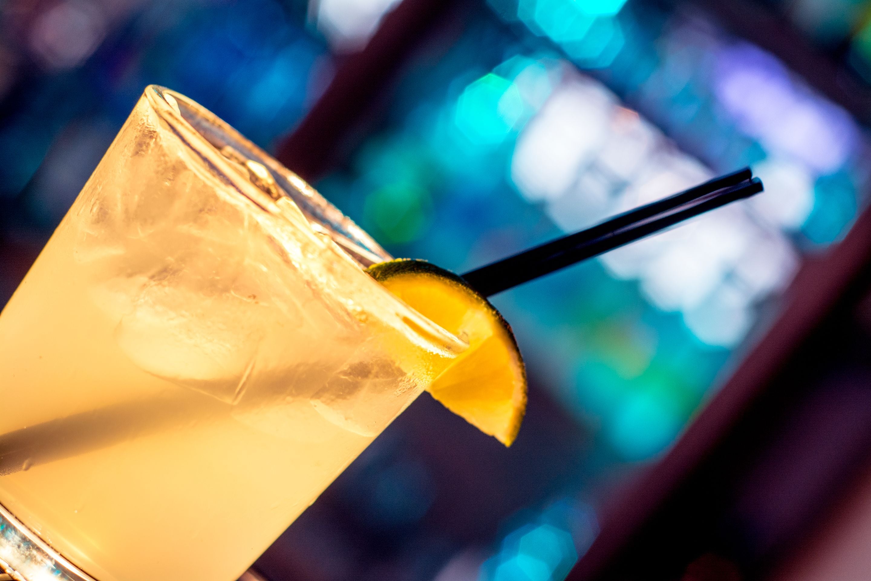 A close-up of a cocktail glass with a lemon slice and a straw.