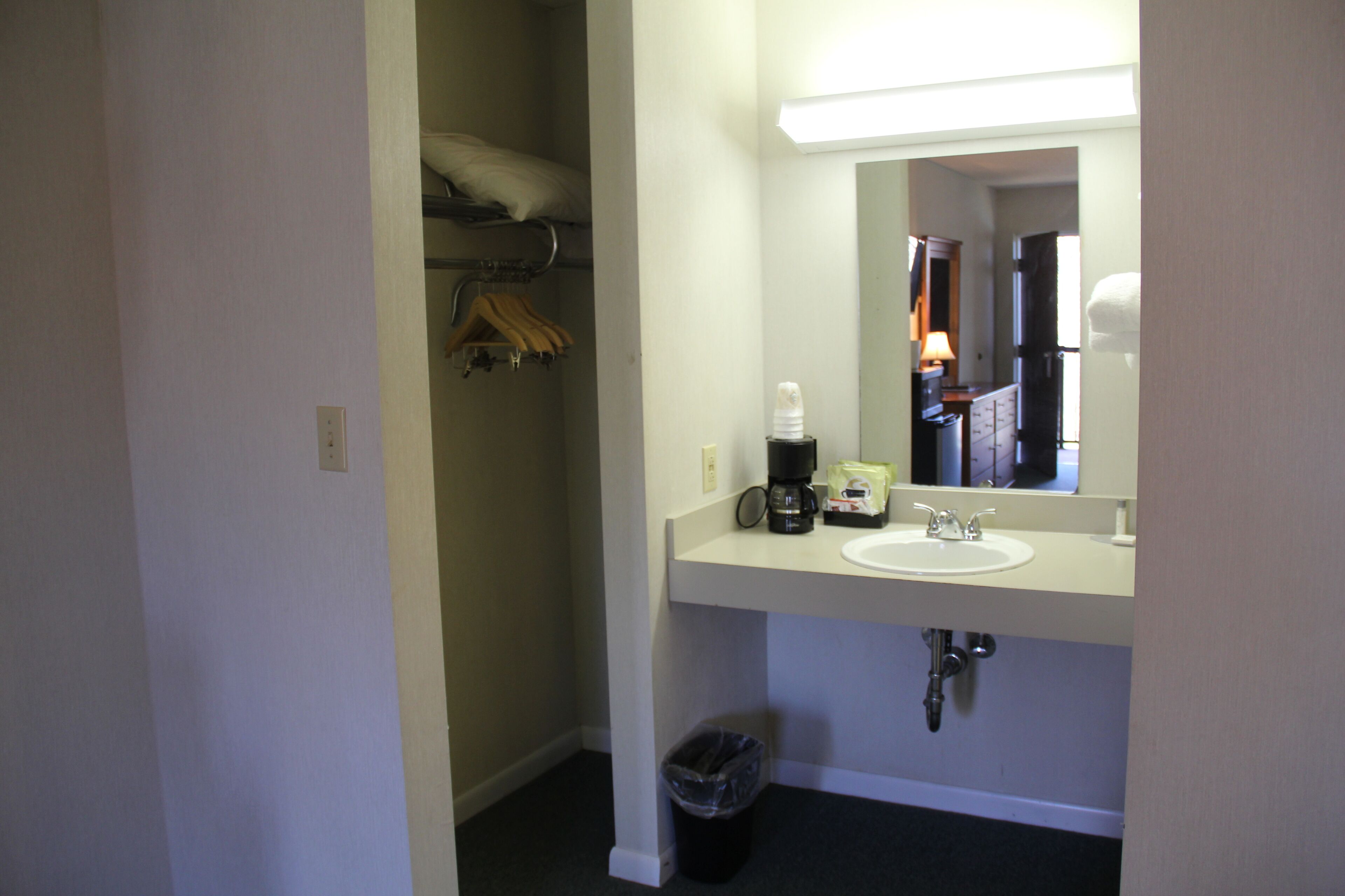 Ein Hotelbadezimmer mit Waschbecken, Spiegel, Kaffeemaschine und Mülleimer.