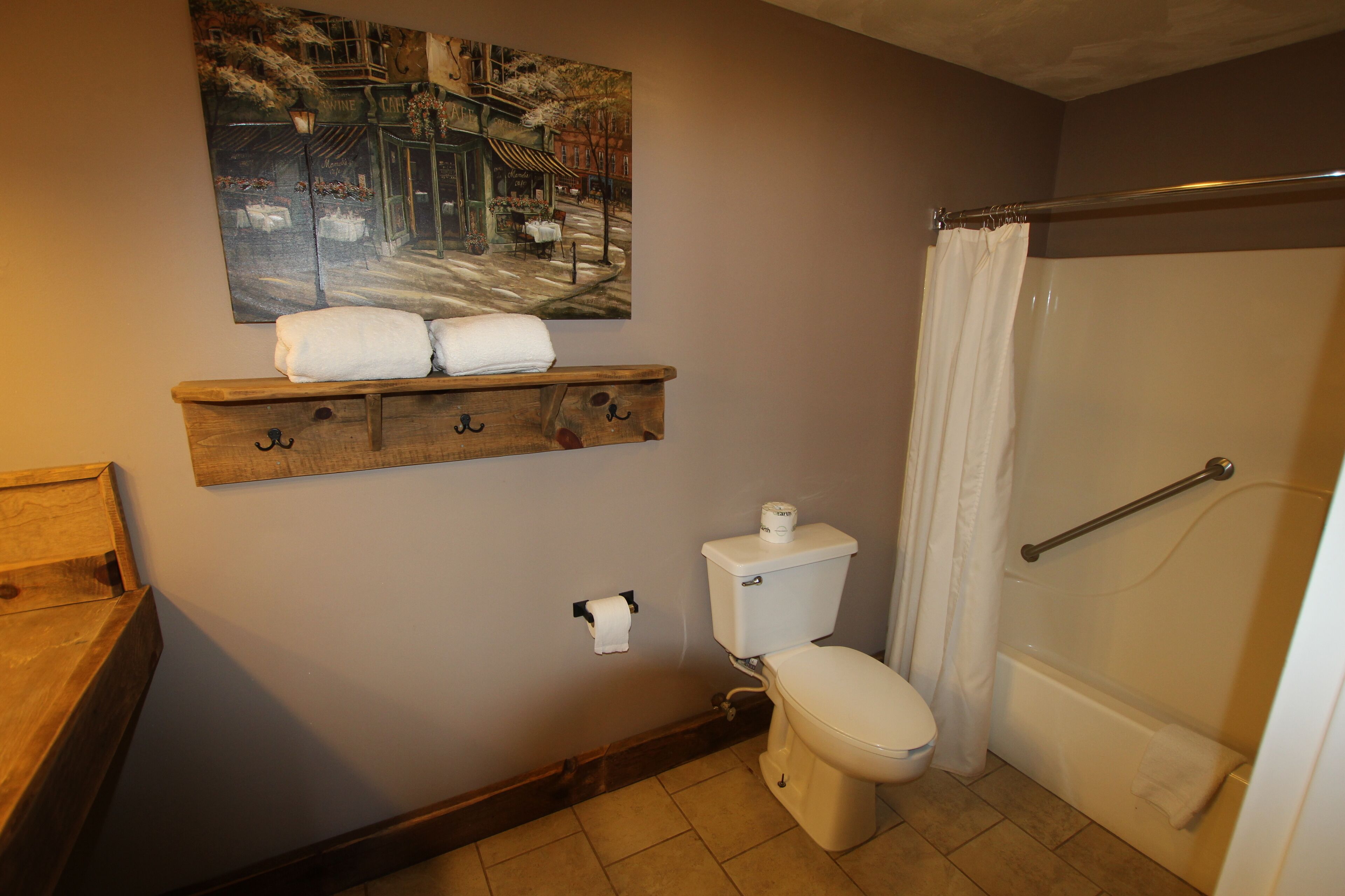 Une salle de bain avec des toilettes, un rideau de douche, un porte-serviettes et un tableau au mur.