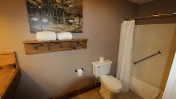 Une salle de bain avec des toilettes, un rideau de douche, un porte-serviettes et un tableau au mur.
