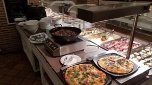 Montaje de bufé con diferentes opciones de comida, incluyendo pizzas y una olla caliente.