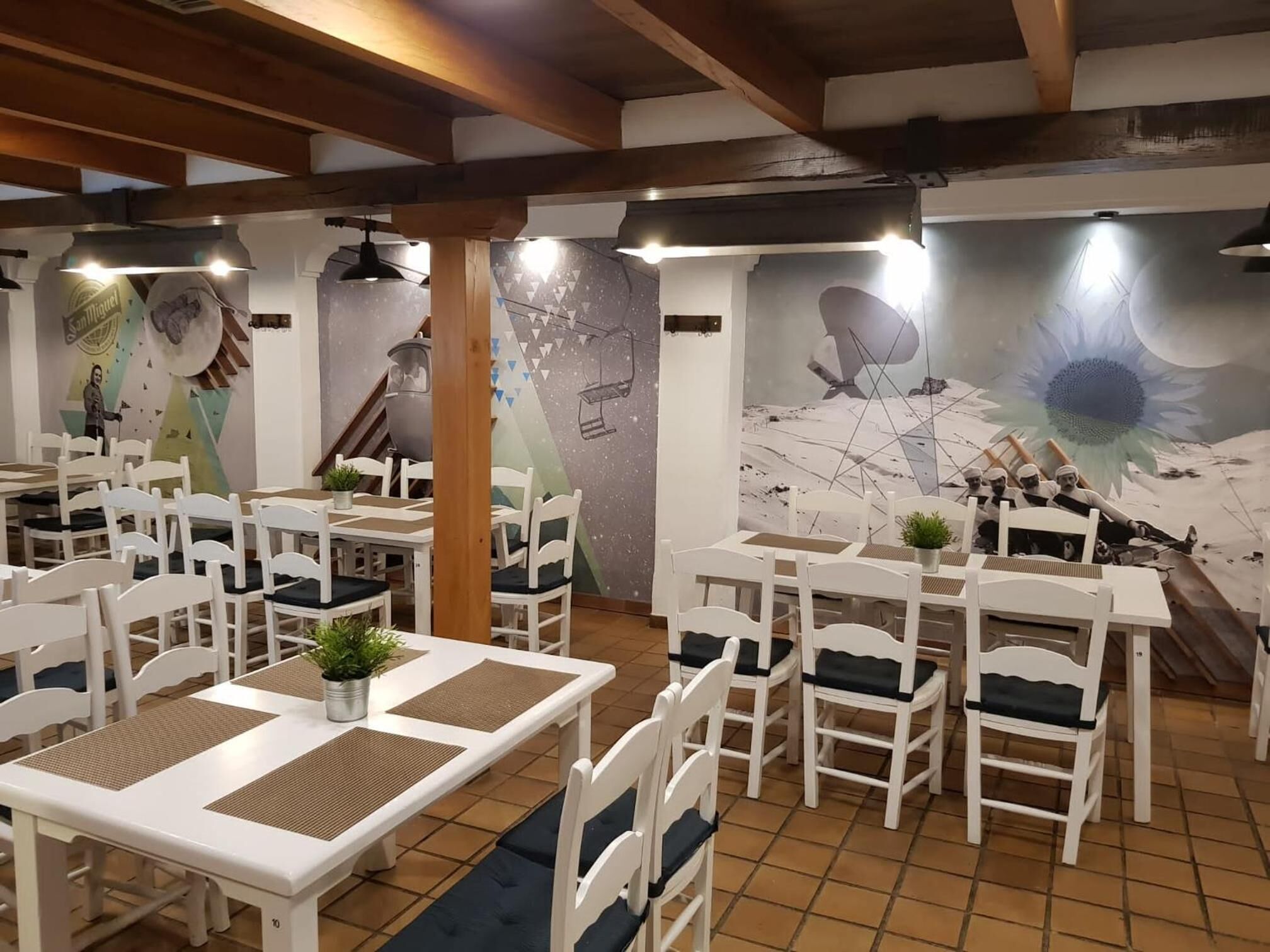 Un restaurant avec des tables et des chaises blanches, une fresque murale et un sol carrelé.