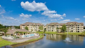 A multi-story hotel with a swimming pool and a lake. - Cane Island Resort by Amazing Vacation Homes FL. Inc (Kissimmee)