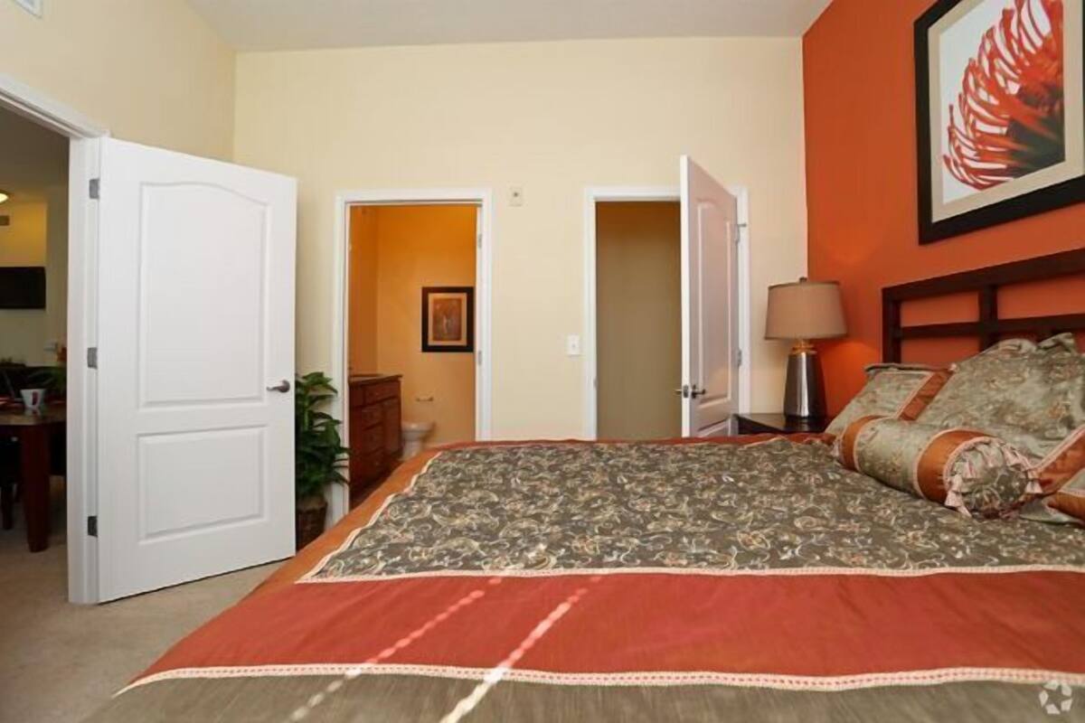 Ein Schlafzimmer mit einem großen Bett, einem Nachttisch mit Lampe und einem Gemälde an der Wand.