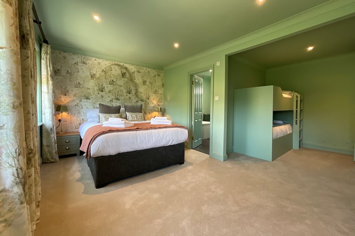 Une chambre à coucher comprenant un lit, des lampes de chevet, une table de chevet, un miroir et une porte donnant sur une autre pièce.