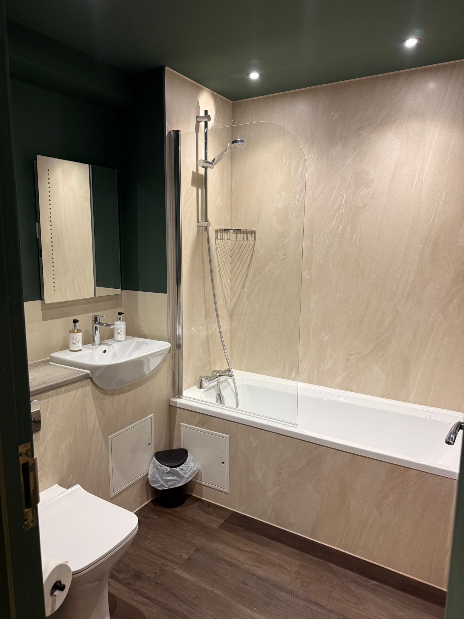 A modern bathroom with a sink, mirror, toilet, and bathtub.
