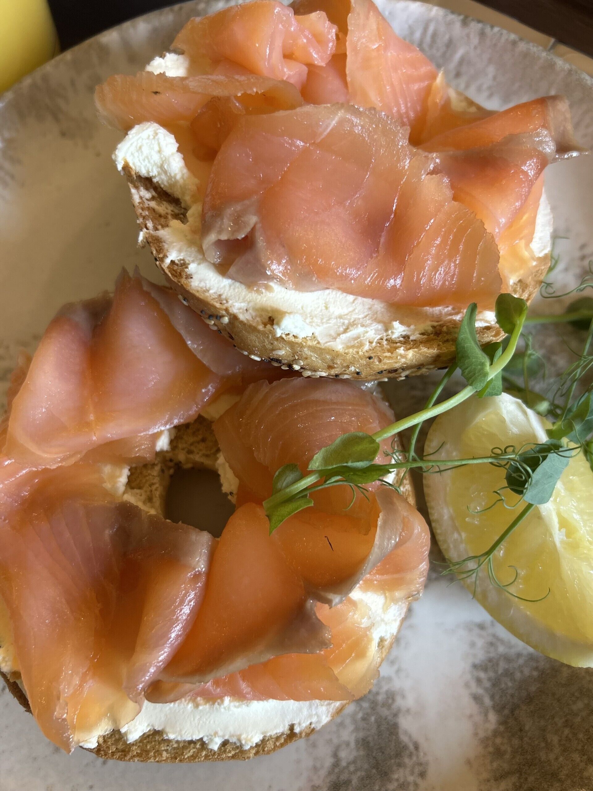 A sandwich with smoked salmon on a slice of bread, garnished with a sprig of herb and a lemon wedge.
