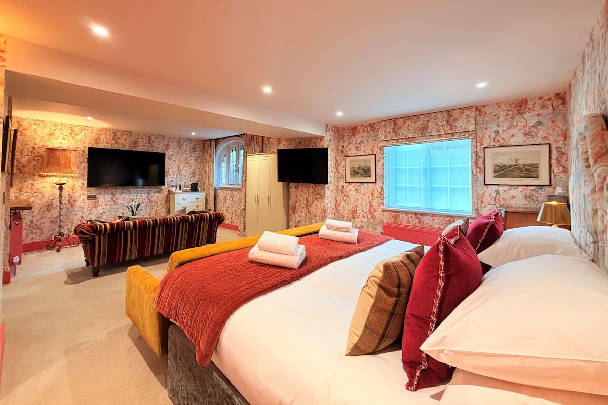 Une chambre d’hôtel avec un lit, un canapé, une télévision, une fenêtre et une porte.