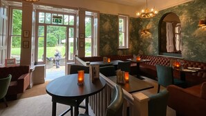 Een restaurant met uitzicht op de tuin, met een ronde tafel, banken en een open haard.