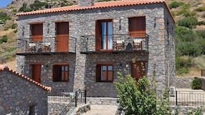 A stone building with multiple balconies and wooden doors. - Vrachos Villas (Agios Vasileios)
