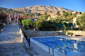 Una piscina al aire libre, sombrillas, sillones reclinables de piscina