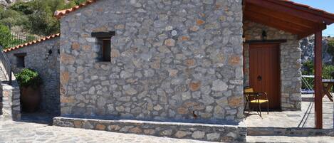 Un edificio de piedra con tejado de tejas, una puerta de madera y un pequeño porche.