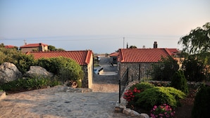 A stone pathway leading to a village with red-tiled roofs and stone houses. - Vrachos Villas (Agios Vasileios)