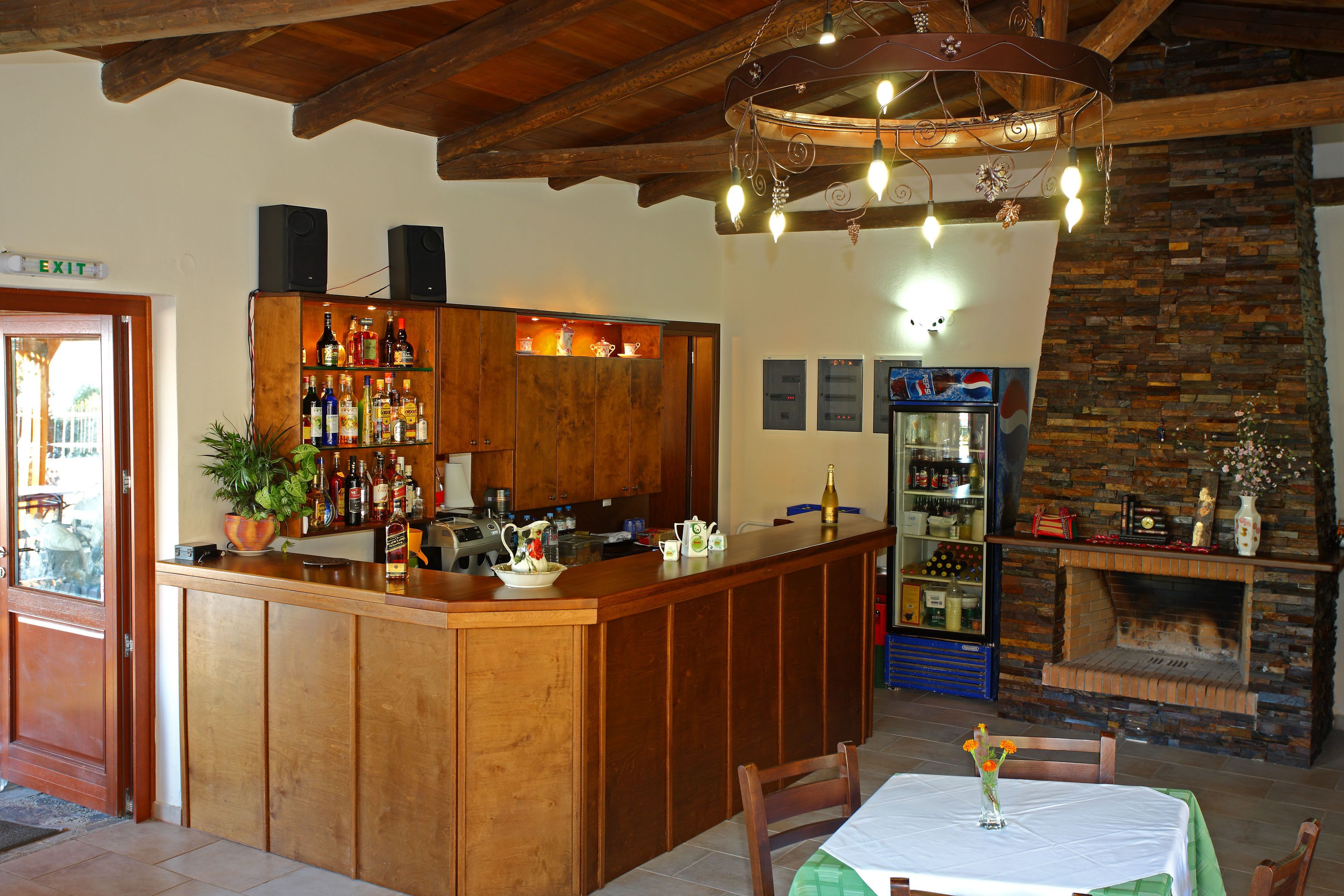 Zona de bar amb armaris de fusta, un taulell i una llar de pedra.