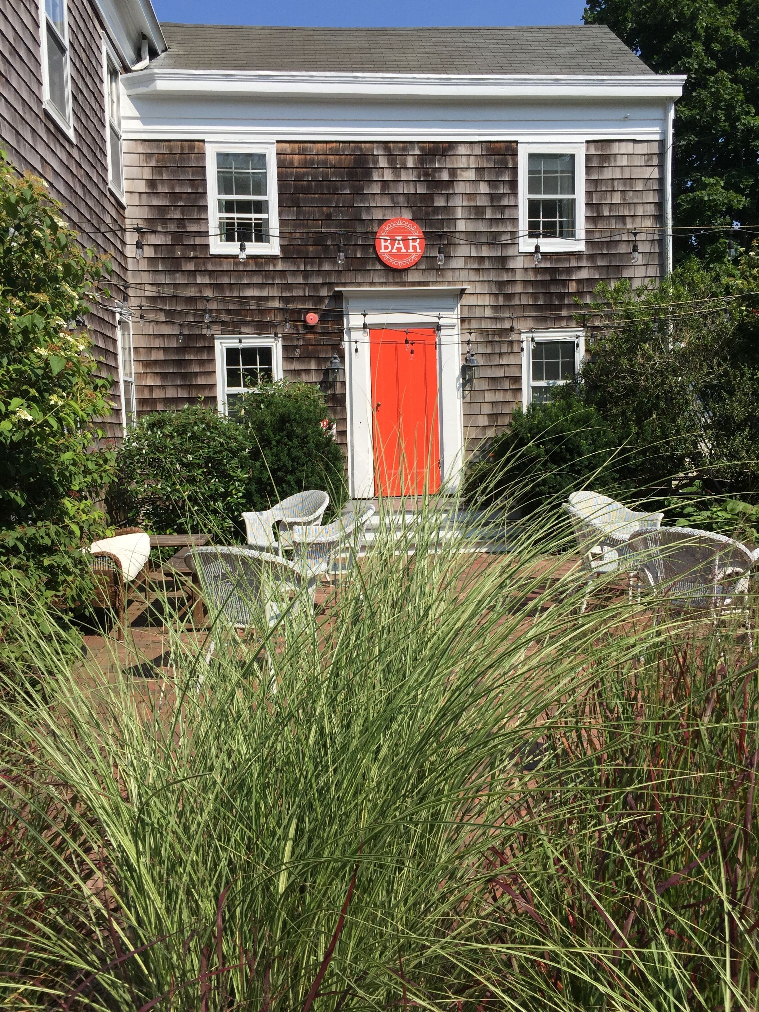 Un bâtiment à deux étages avec une porte rouge et une enseigne « BAR » au-dessus.