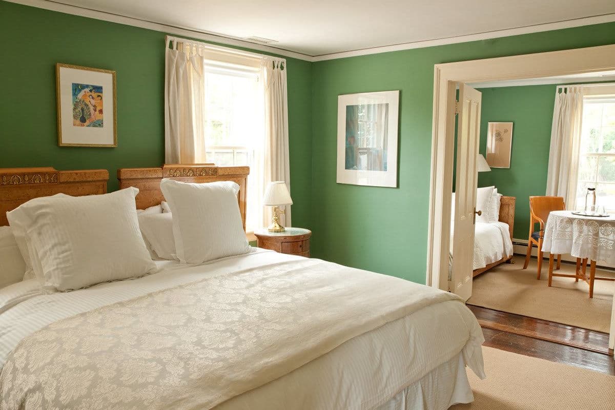 A bedroom with a large bed, two bedside tables, a chair, and a small table with a lamp.