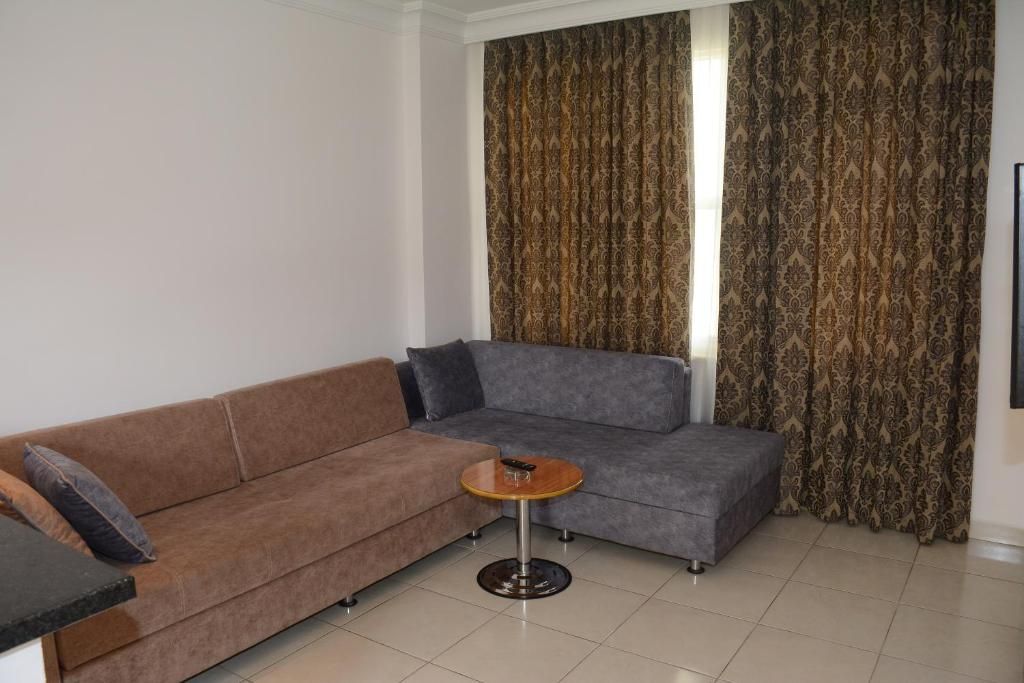 Ein Wohnzimmer mit einem braunen Sofa, einer grauen Eckcouch und einem kleinen runden Tisch.
