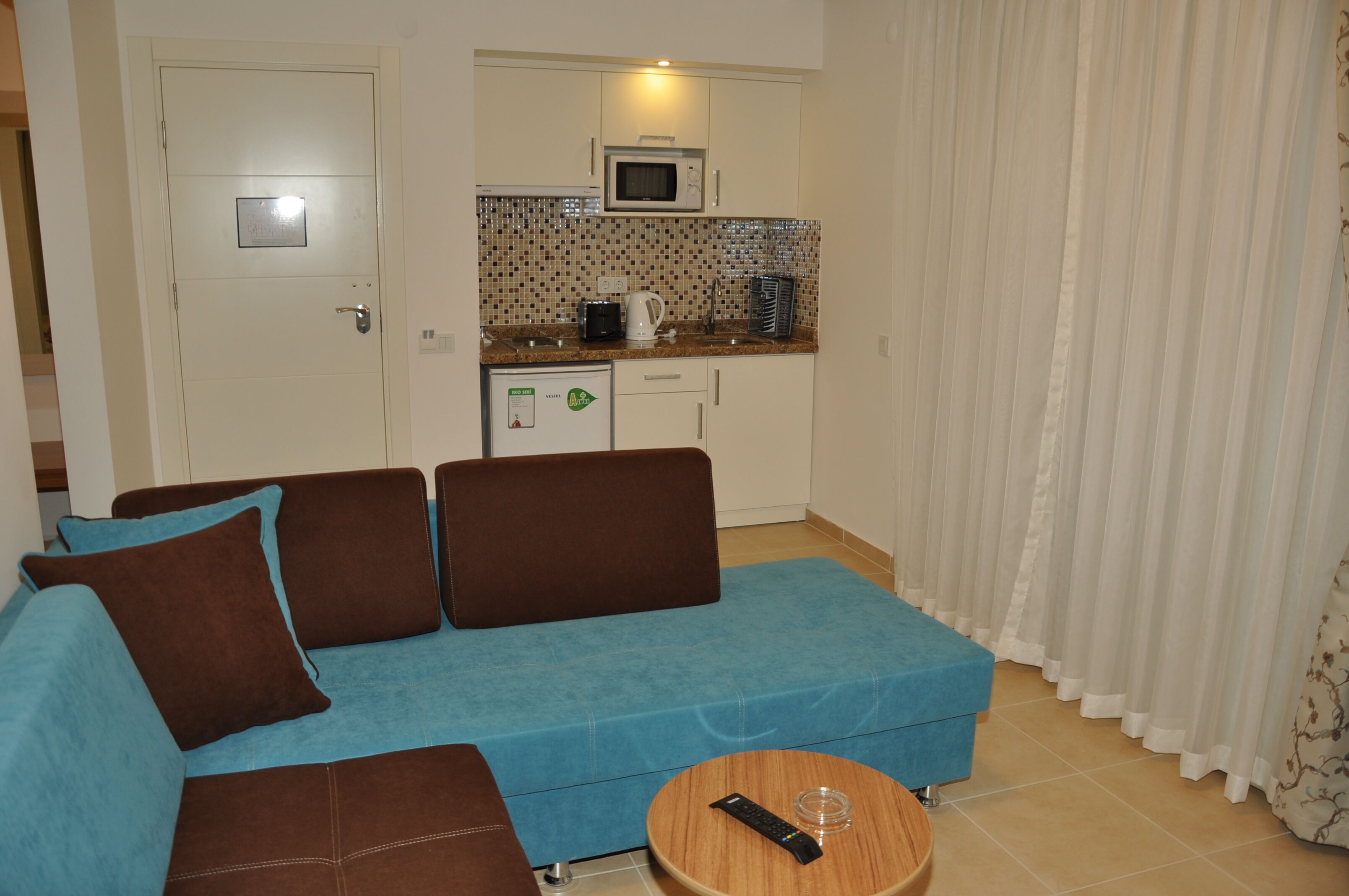 A compact living space with a sofa, a small table, a microwave, and a kitchenette.