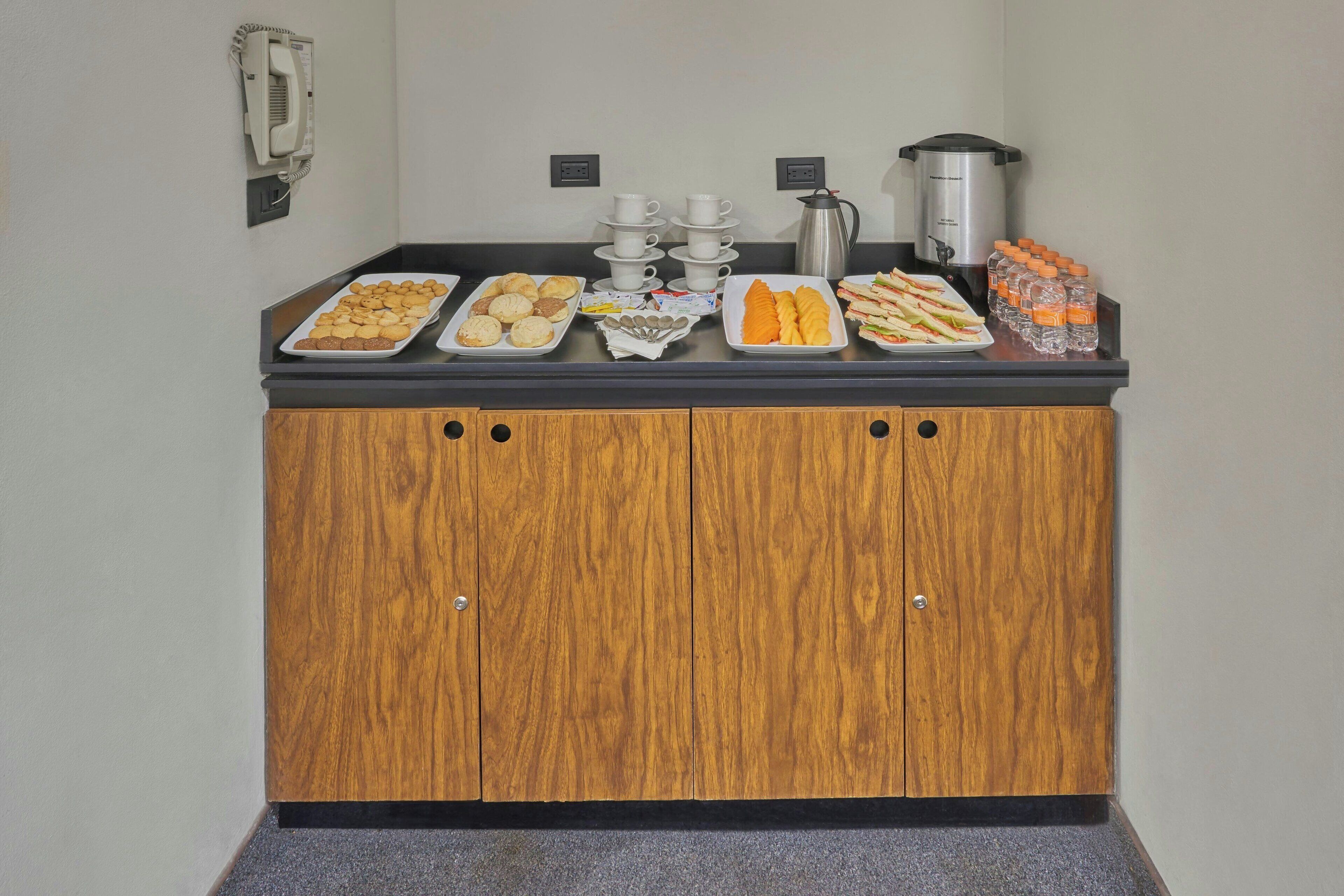 A buffet counter with various food items, a coffee station, and a water dispenser.