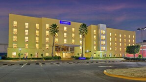 Un hotel CITY EXPRESS con una fachada moderna, varios pisos y una entrada bien iluminada.