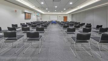 Ein Konferenzraum mit schwarzen Stühlen, einer Projektionsleinwand und einem Teppichboden.