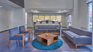 Un lobby moderno con asientos, una mesa de centro y un ventanal con vistas.