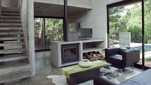 Una sala de estar moderna con chimenea, televisor y una escalera que sube a otro nivel.