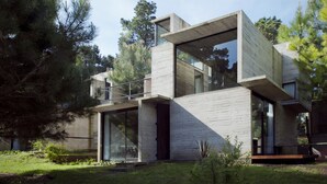 Una casa moderna con un diseño arquitectónico único, que presenta grandes ventanales y un techo plano.