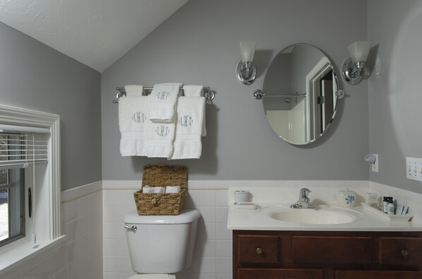 Une salle de bain comprenant des toilettes, un lavabo, un miroir et un porte-serviettes avec des serviettes.