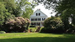 A large white house with a symmetrical facade, a central entrance with steps, and a well-maintained garden. - Liberty Hill Inn (Yarmouth Port)
