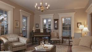 A living room with a piano, multiple chairs, a coffee table with a tray of cookies and wine glasses, and a chandelier. - Liberty Hill Inn (Yarmouth Port)
