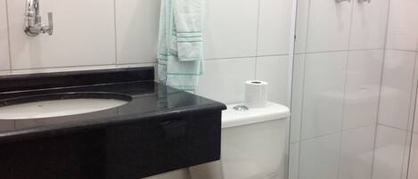 Une salle de bain avec un lavabo noir, des toilettes blanches et une douche à parois de verre.