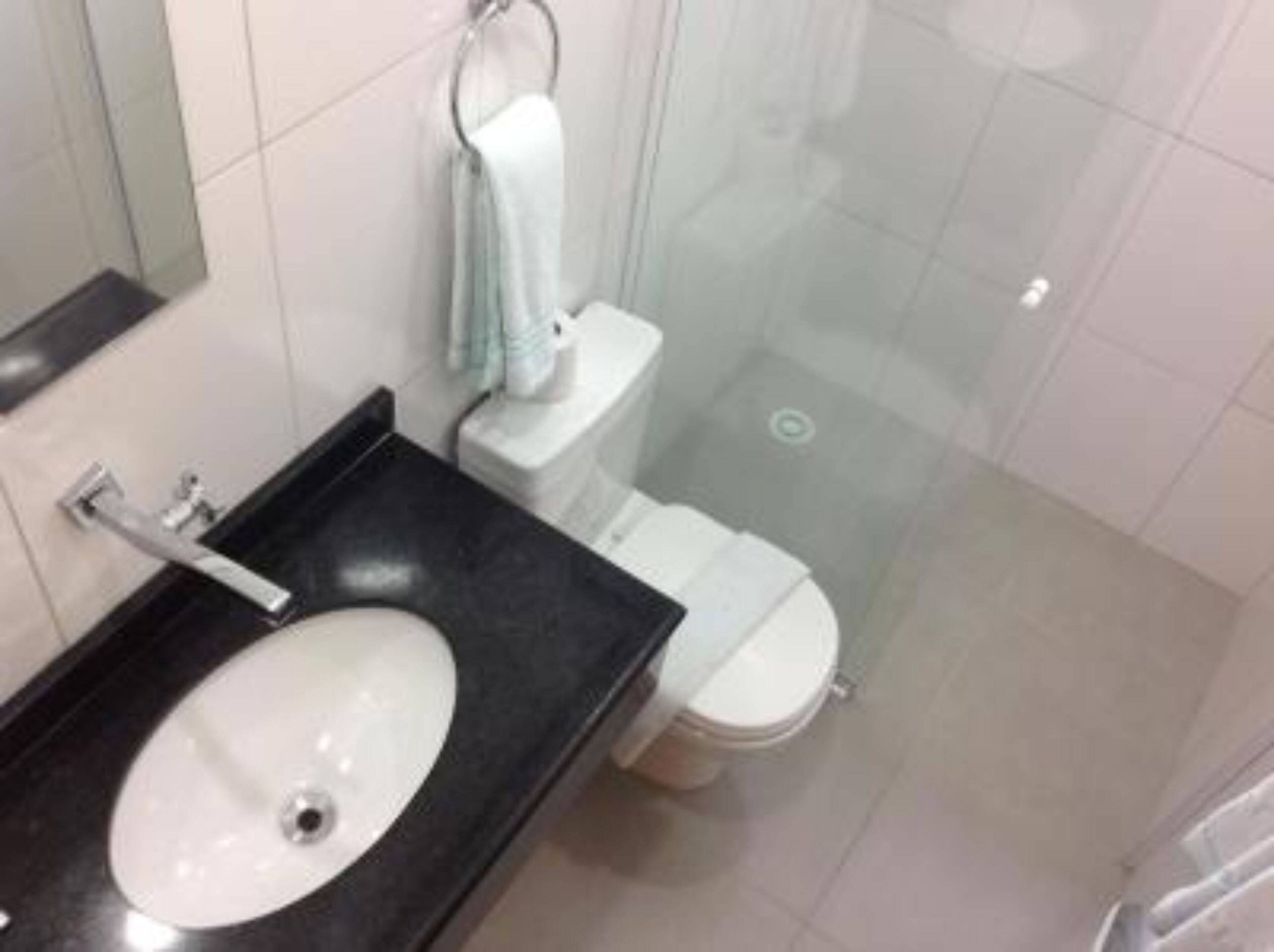 Un baño con un lavamanos blanco, un inodoro y una cabina de ducha de cristal.
