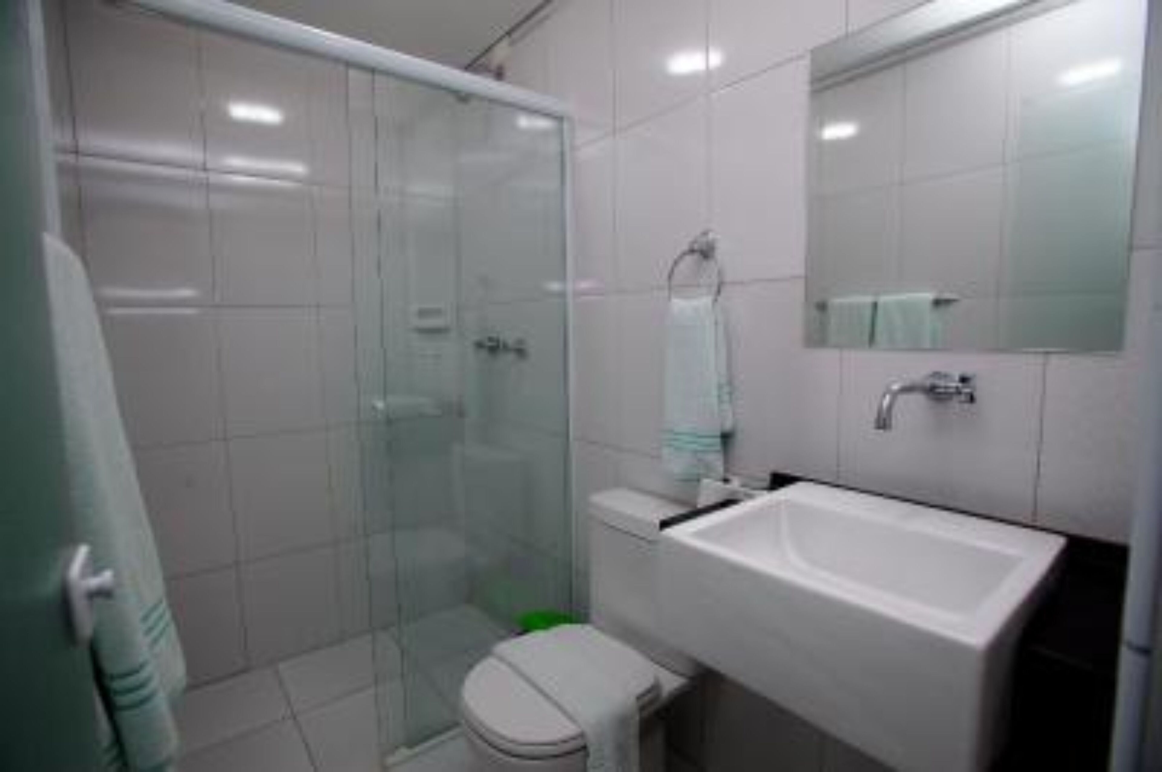Een moderne badkamer met een douchecabine van glas, een wit wastafelmeubel en een toilet.