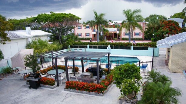 A pool area with a covered patio, outdoor furniture, and a barbecue grill. - Holiday House Motel (Lake Worth)